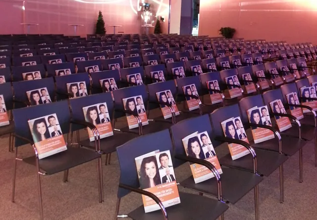 Saal vor einem Vortrag von Carmen Brablec, ihr Buch liegt auf jedem Stuhl